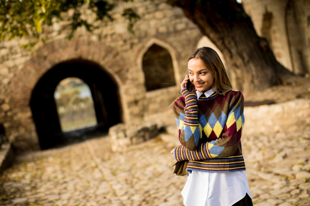 pretty-young-woman-standing-with-mobile-phone-on-s-2023-11-27-05-36-51-utc-scaled-1024x683_11zon