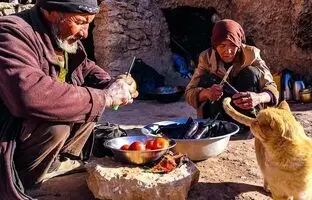 (ویدئو) پخت نان محلی و گوجه بادمجان ذغالی توسط زوج مسن غارنشین افغانستانی