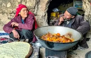 (ویدئو) پخت نان ساجی و یک غذای محلی با ران گوسفند توسط زوج غارنشین افغانستانی